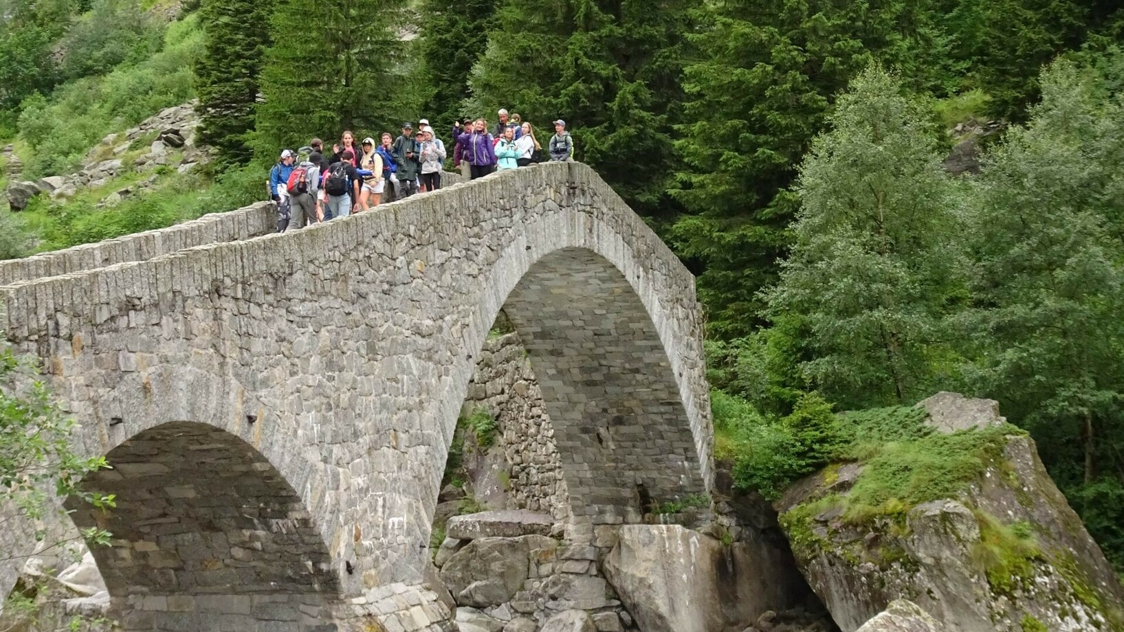 Eine Schulklasse auf einer alten Steinbrücke am Gotthard