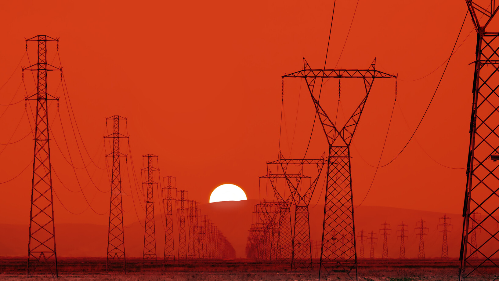 Strommasten vor einem Sonnenuntergang. Der Himmel ist ganz rot.