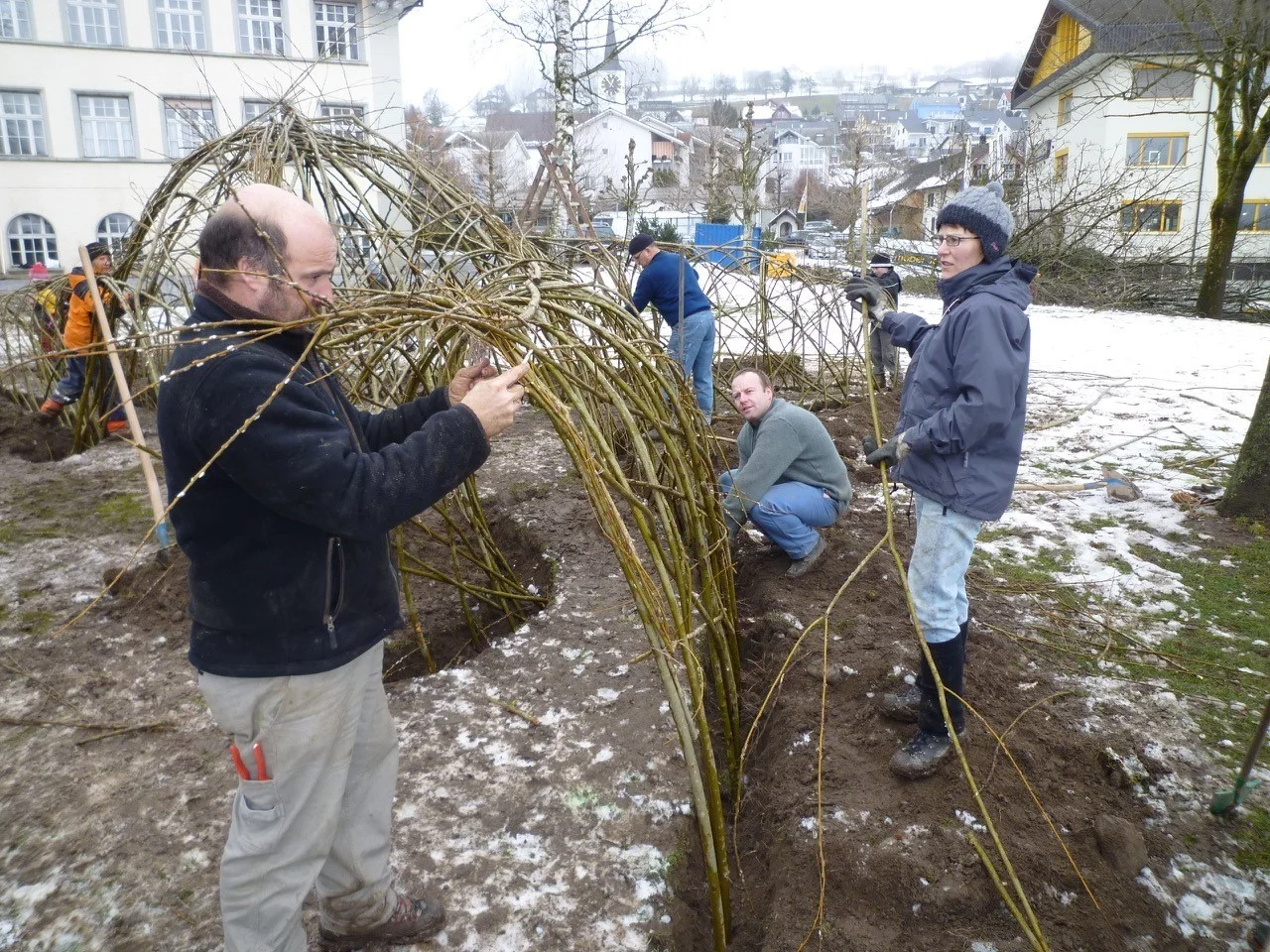 Eine Gruppe beim Bauen eines Weidengebildes auf einem Schulhausplatz