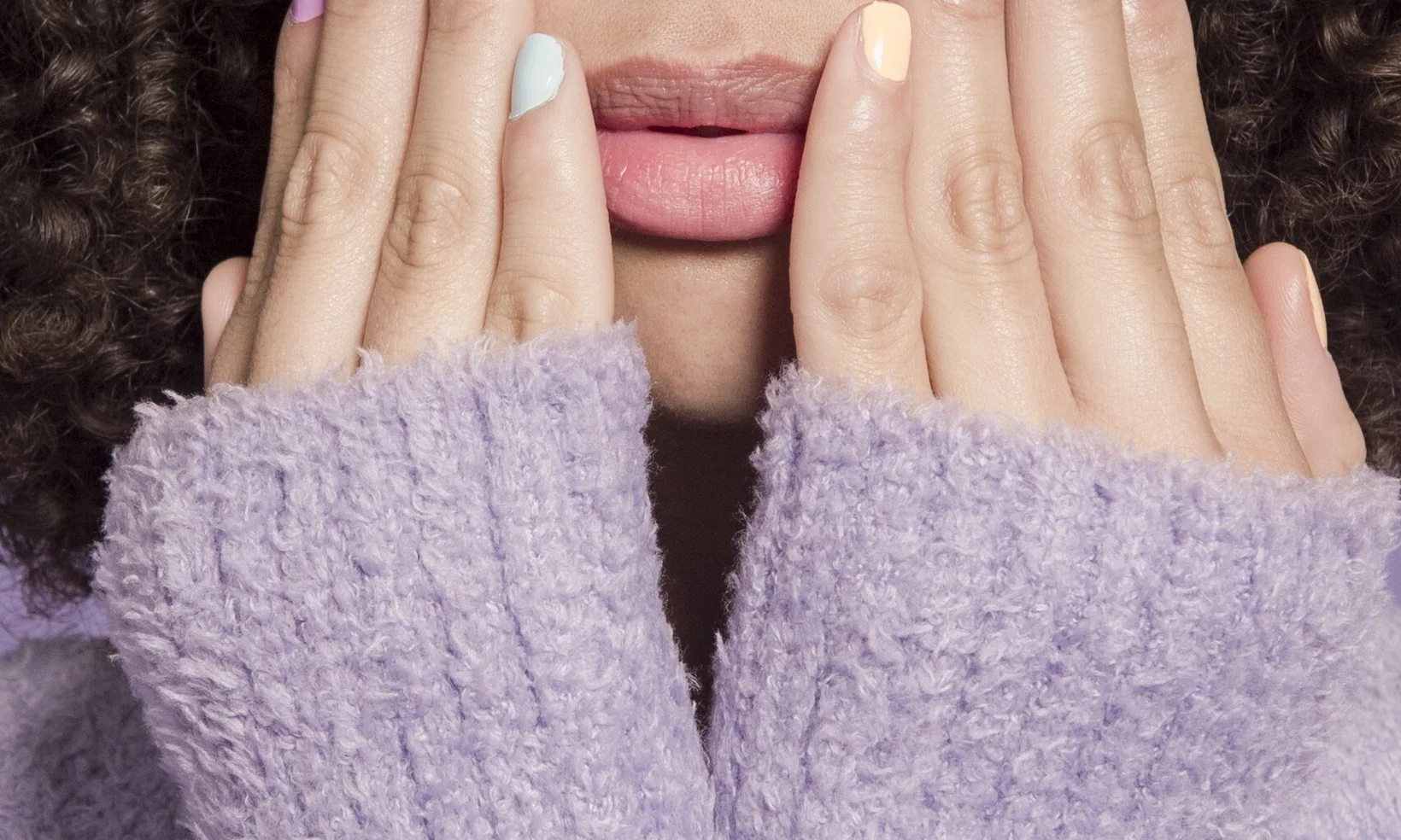 Thoughtful ethnic woman touching face with hands with pastel nails