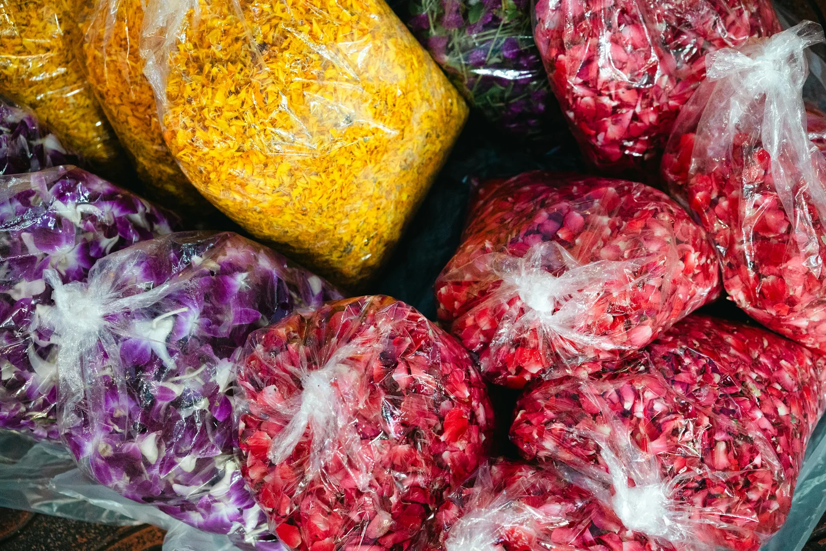 Vibrant packs of colorful flower petals wrapped in plastic bags, ready for sale.