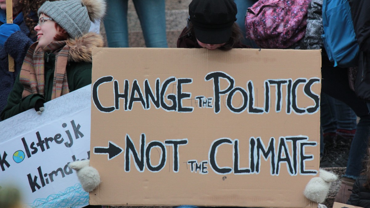 Person hält ein Plakat mit der Aufschrift: Change the politics, not the climate