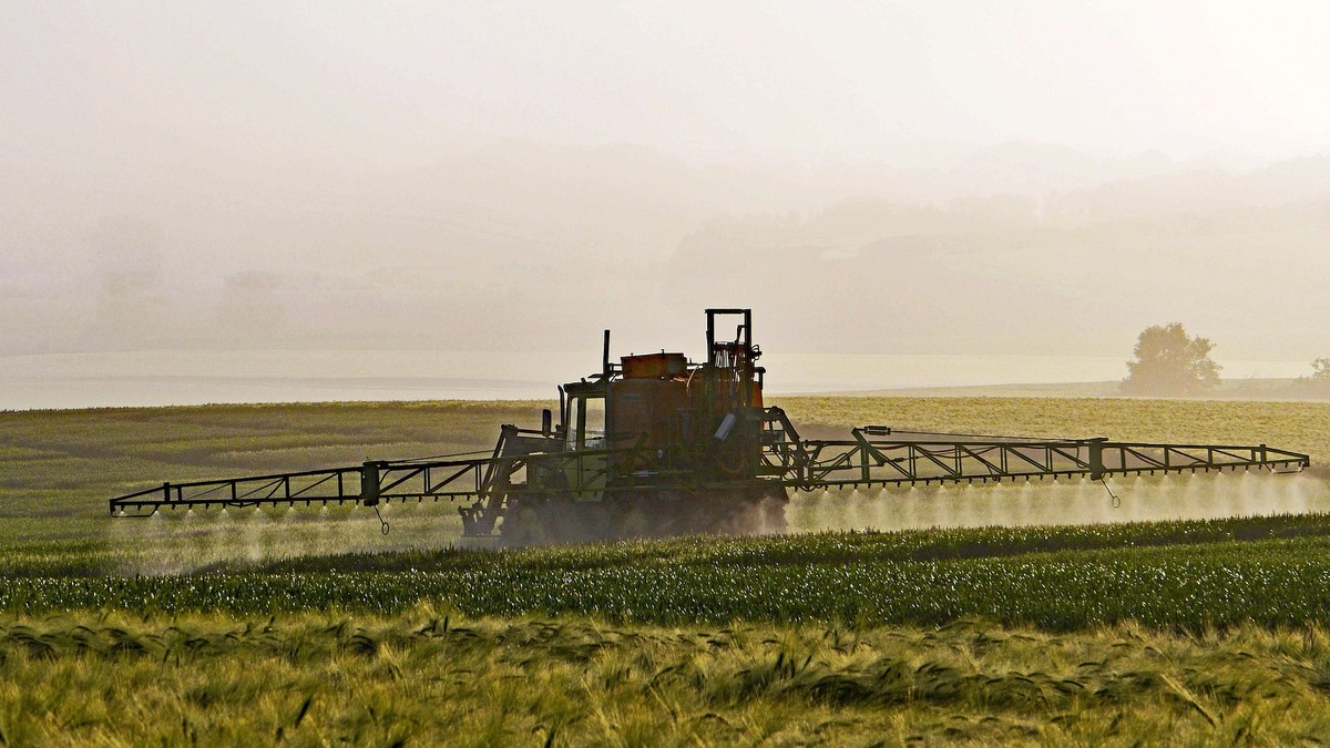 Ein Traktor spritzt Pestizide auf einen Acker