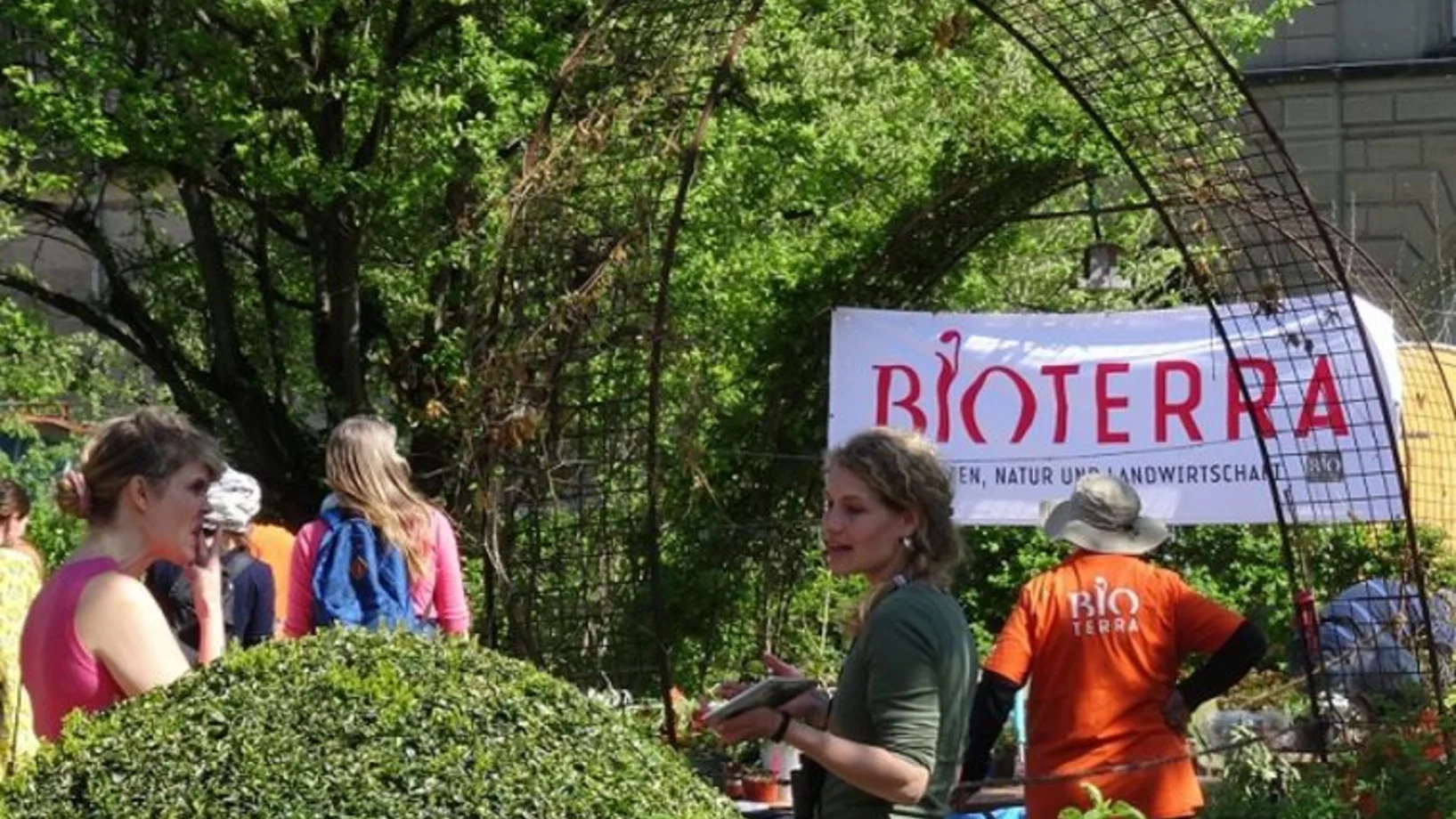 Verschiedene Personen in einem grünen Garten. Im Hintergrund ein BioTerra-Banner