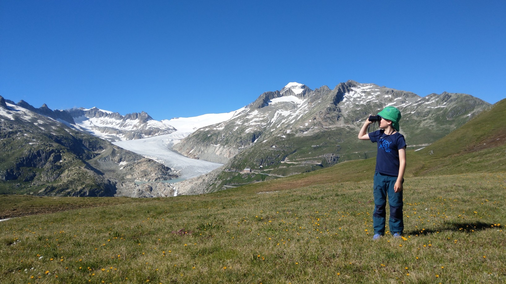 Kind beobachtet den schwindenden Gletscher mit dem Feldstecher