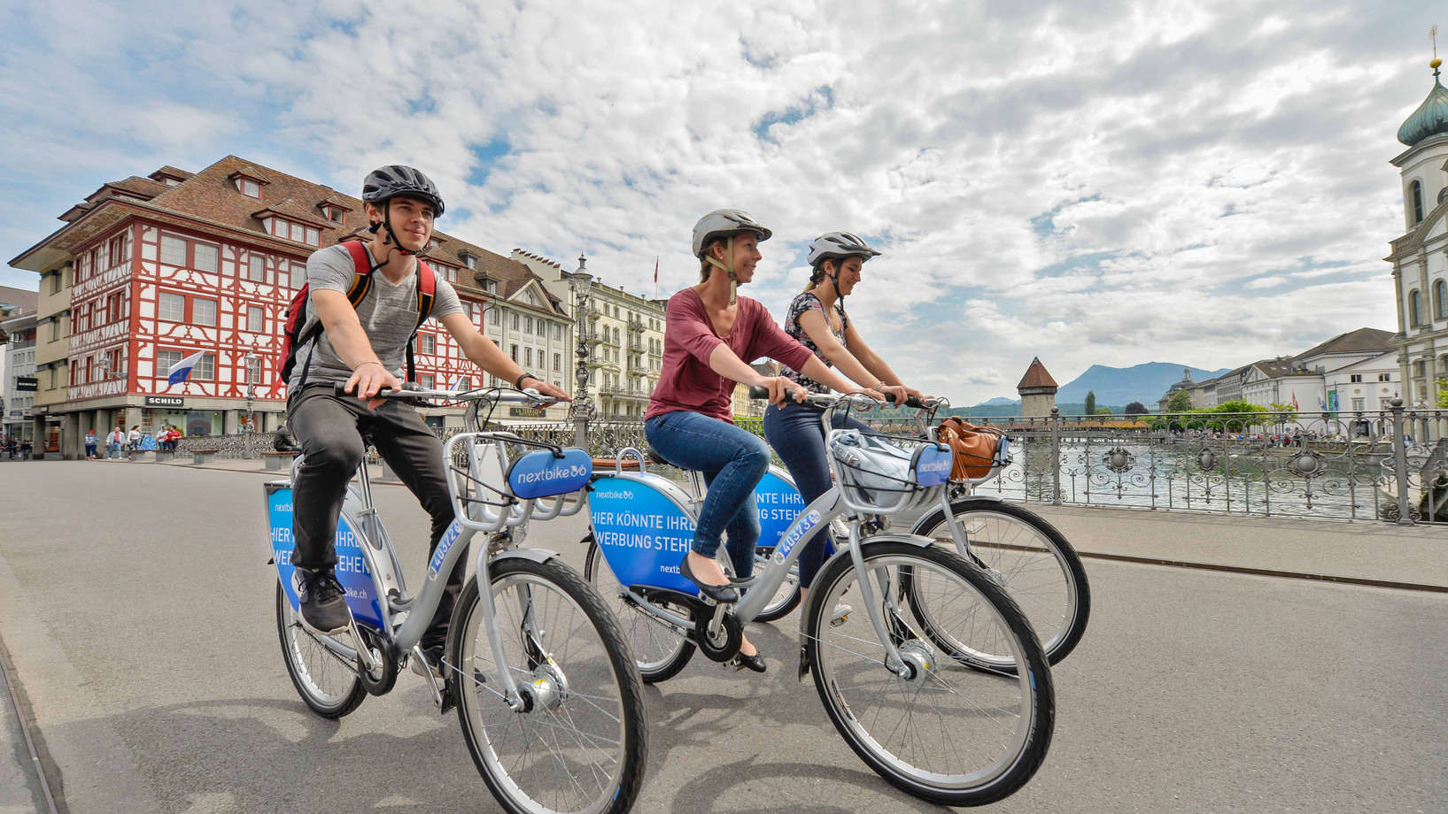 Drei Personen fahren auf Nextbike-Velos über eine Brücke