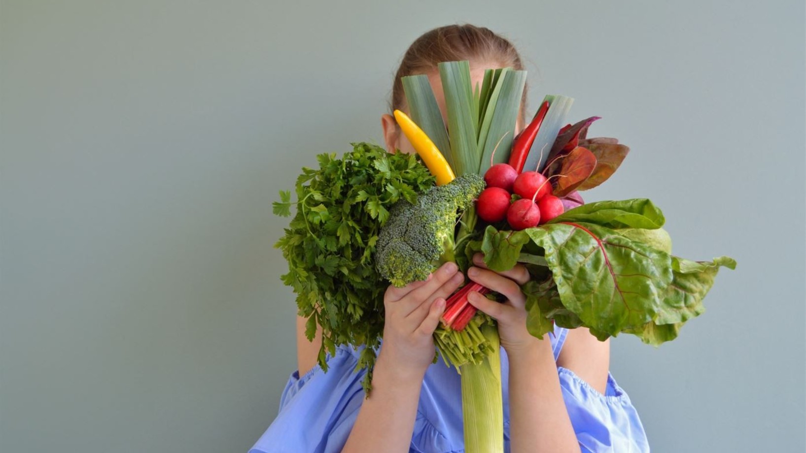 Eine Frau hält sich Gemüse vors Gesicht