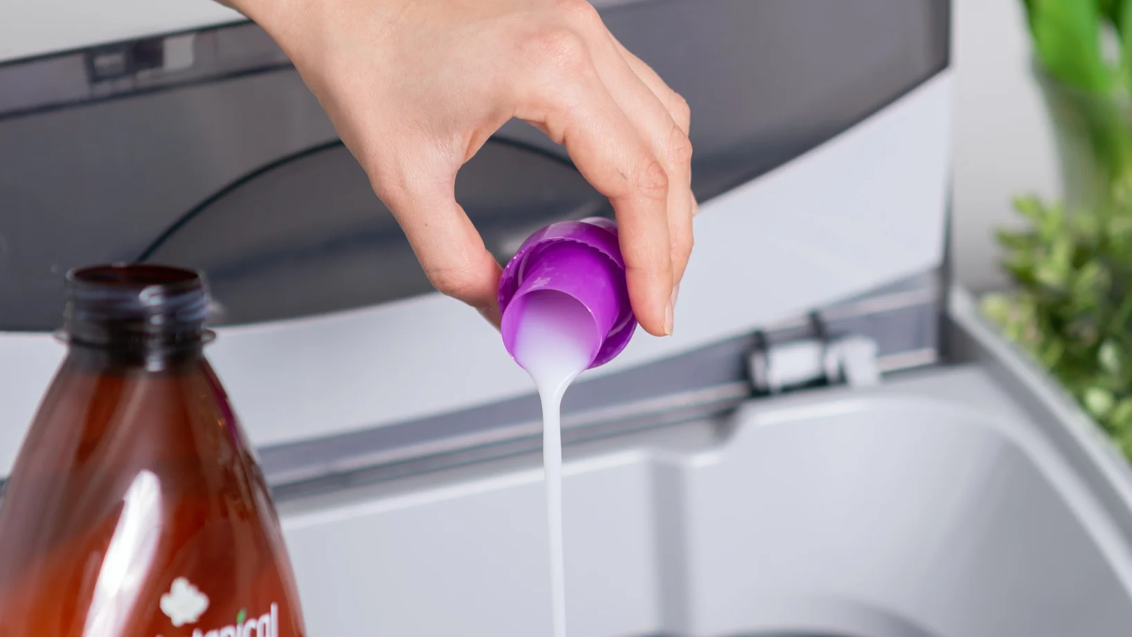 Eine Frau kippt einen Becher Waschmittel in die Maschine