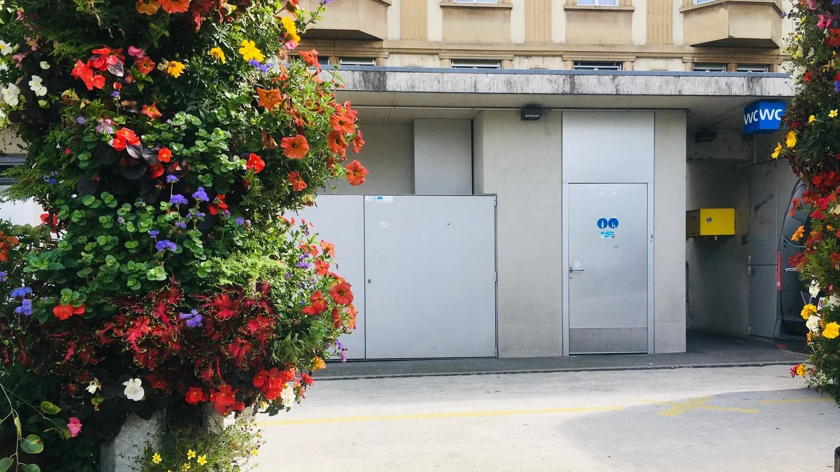 WC-Anlage beim Löwenplatz mit Blumen im Vordergrund