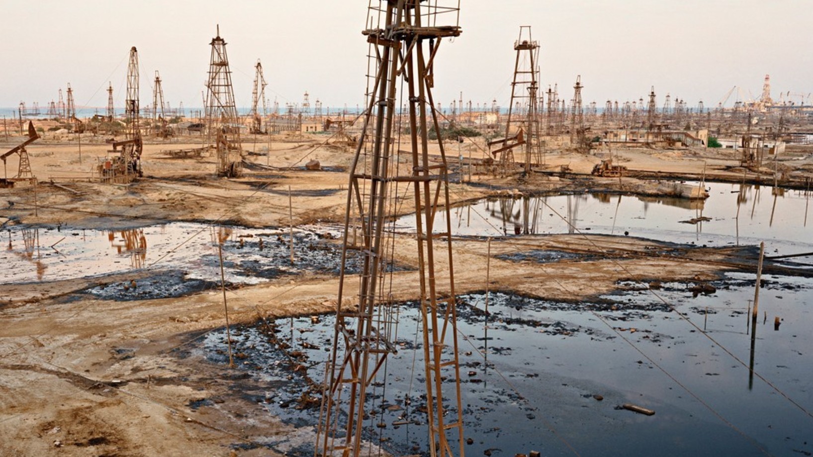 Ein Areal voll mit alten Bohrtürmen und Ölfeldern, welche mit Öl überschwemmt sind.