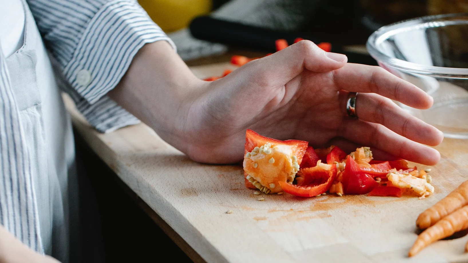 Crop unrecognizable housewife throwing waste while cooking in kitchen