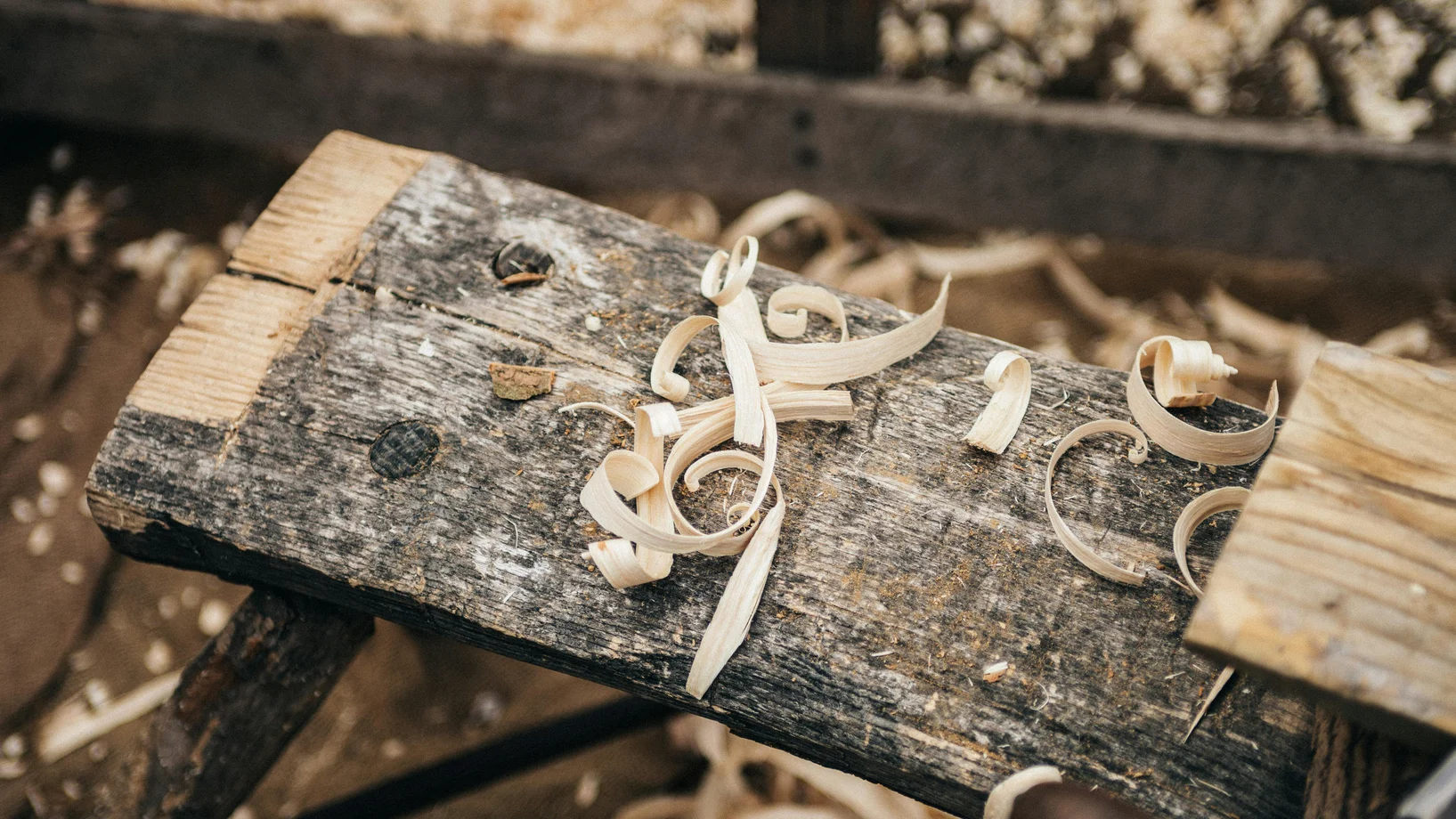 Rustic workbench covered in wood shavings, showcasing detailed craftsmanship.