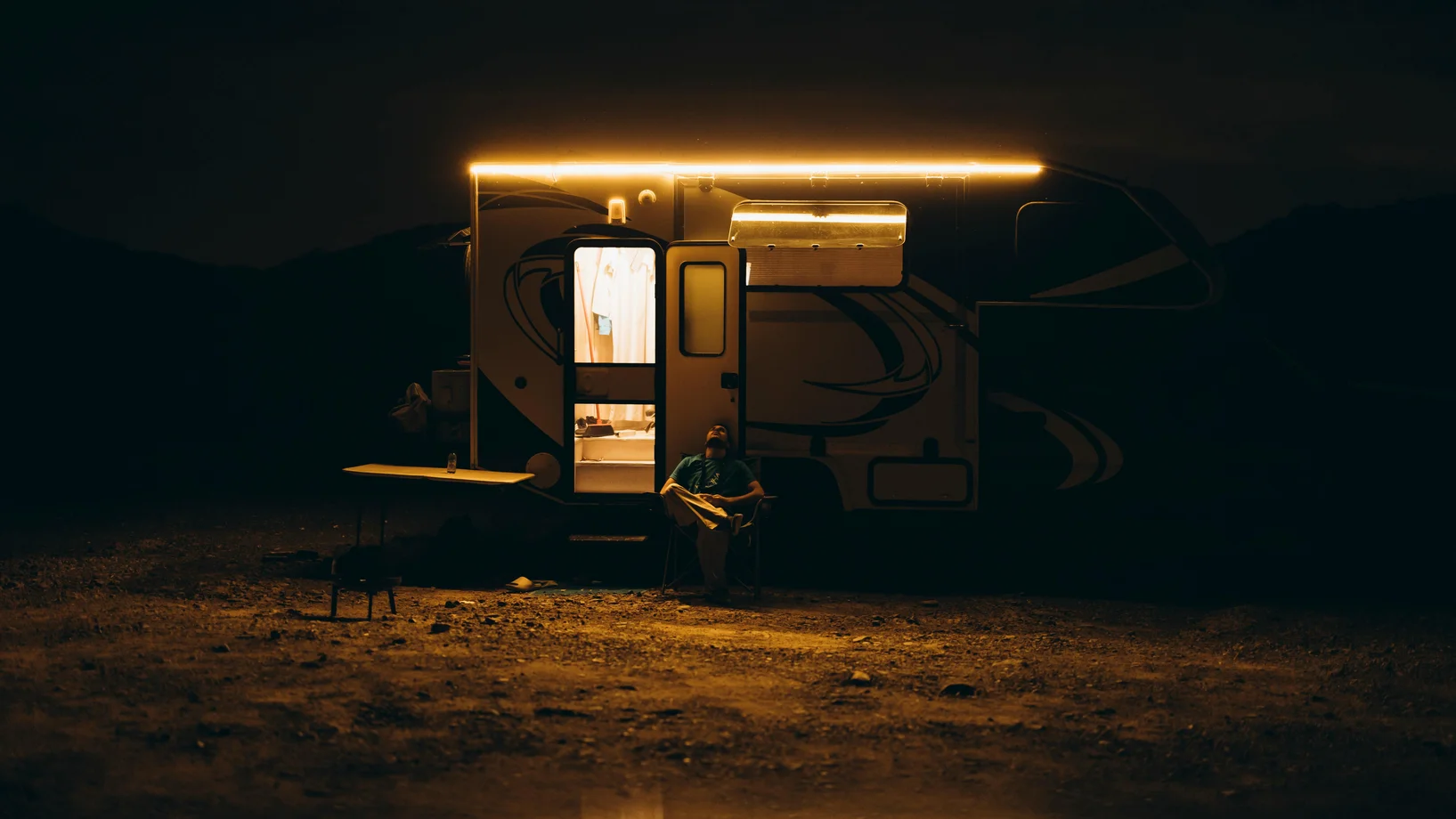 A serene night camping scene with a lit caravan under the Dubai desert sky.