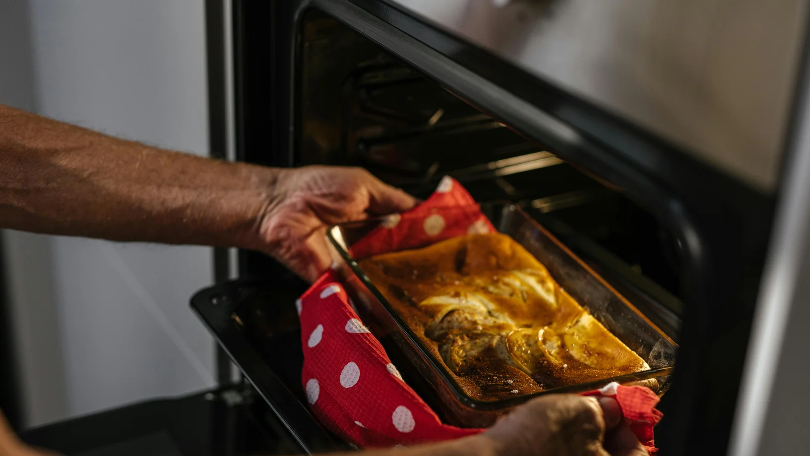 Person removes freshly baked cake from oven, showcasing home baking joy.
