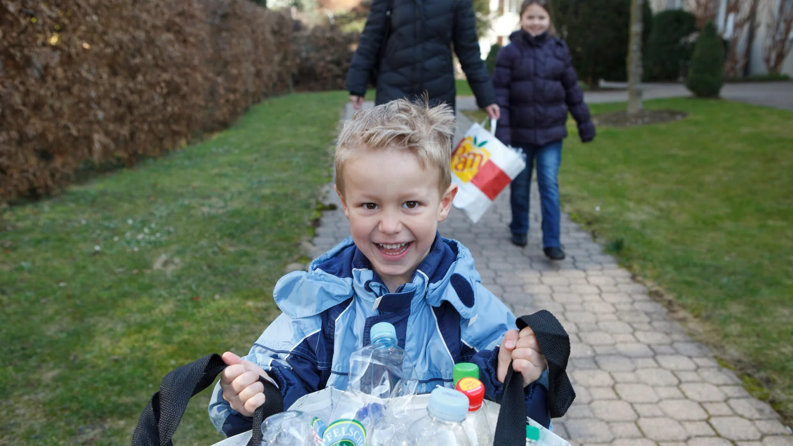 Kind hält Plastiksack voller PET-Flaschen