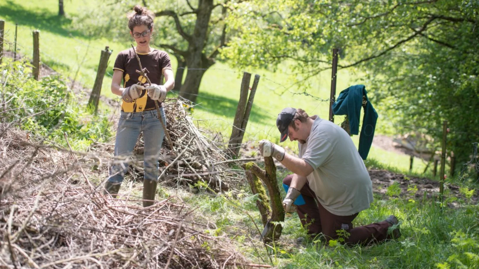 zwei Personen bestücken einen Asthaufen