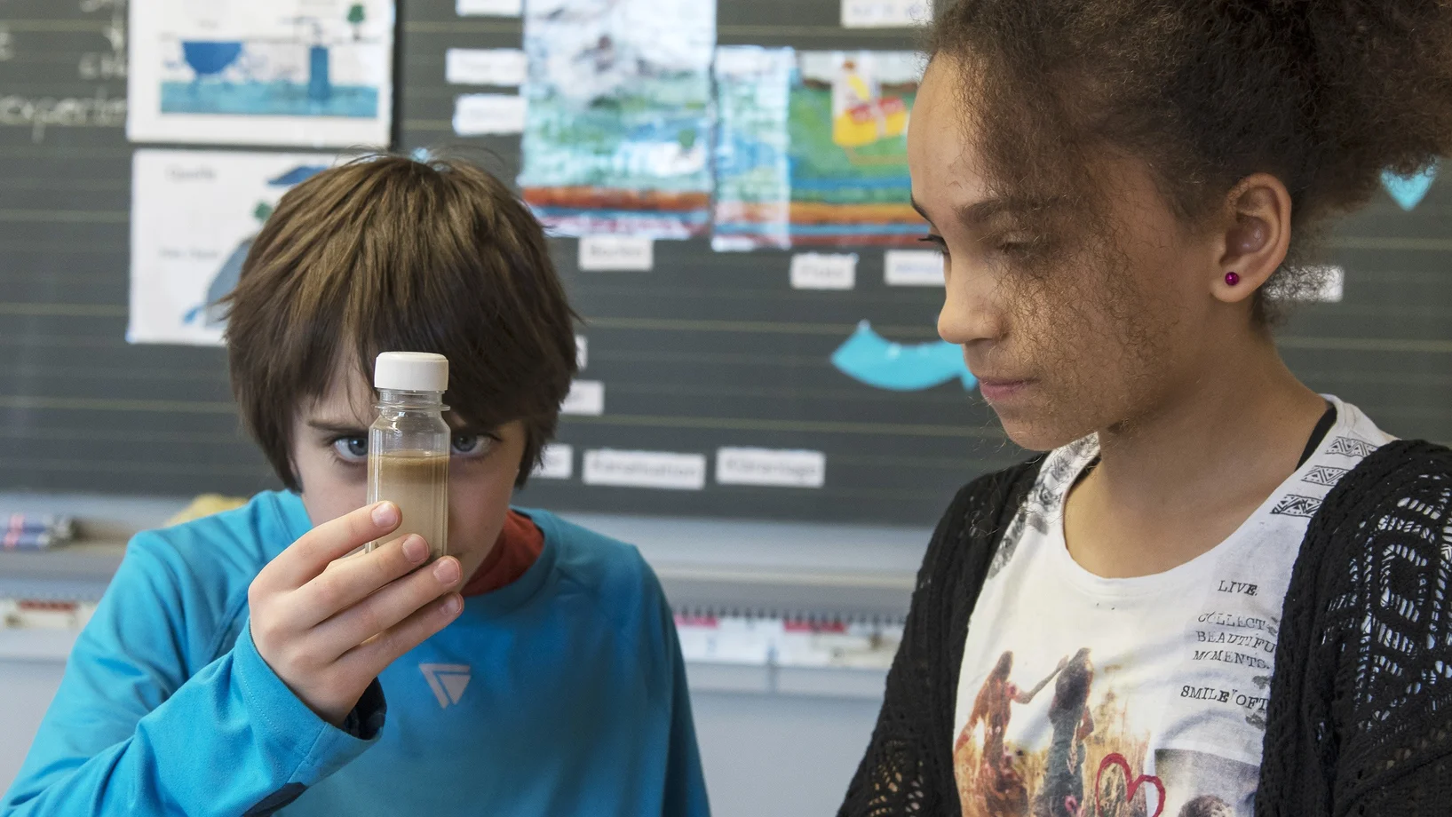 zwei Kinder betrachten eine Wasserprobe