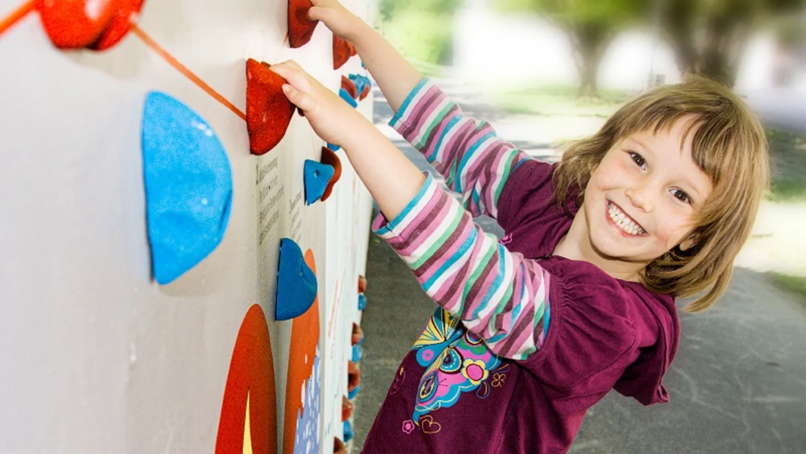 Kind klettert Kletterwand hoch