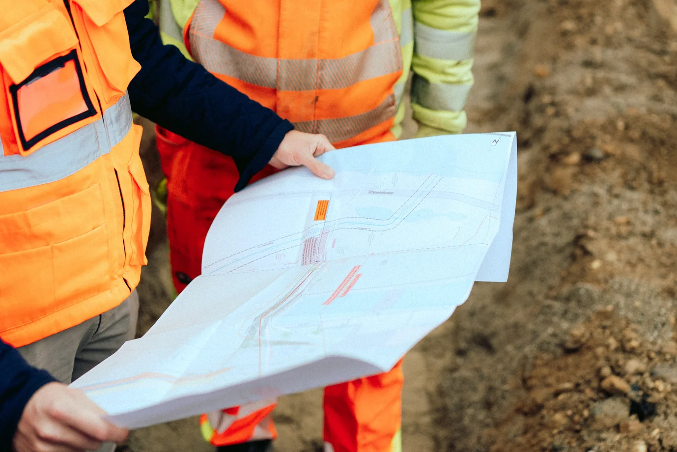 Bauarbeiter:innen mit Plan auf Baustelle